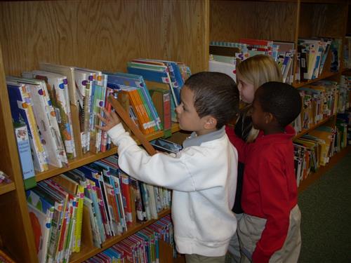 Children checking out books Children checking out books